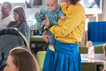 Kobieta stoi na widowni z dzieckiem na rękach.
