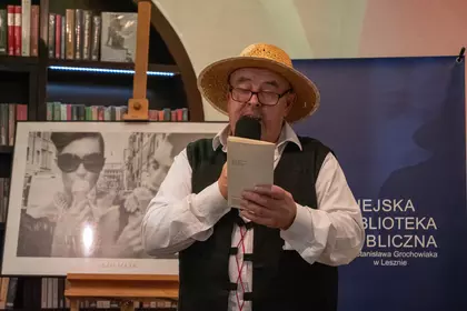 Mężczyzna czyta fragment książki podczas spotkania.