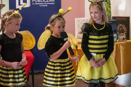 Dzieci w strojach pszczół prezentują się przed publicznością.