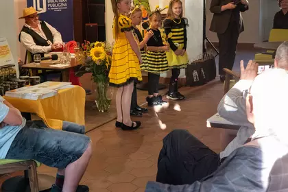 Dzieci w strojach pszczół uczestniczą w spotkaniu bibliotecznym.