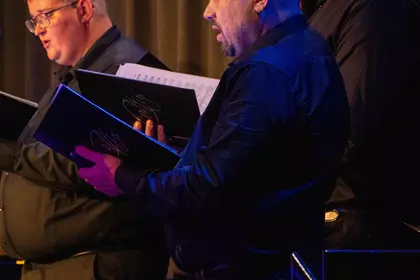 Śpiewacy zespołu Cantus podczas koncertu, z partyturami w dłoniach.