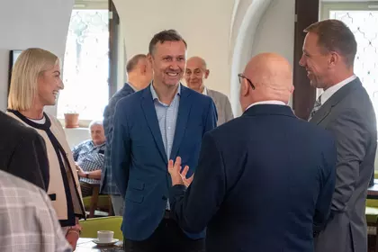 Grupa uśmiechniętych gości wydarzenia rozmawia w przestrzeni Biblioteki Ratuszowej.