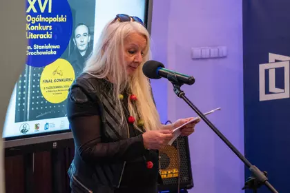 Laureatka odczytuje swój wiersz do mikrofonu.