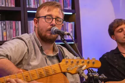 Wokalista śpiewa i gra na gitarze.