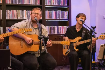 Gitarzyści grają i śpiewają na scenie.
