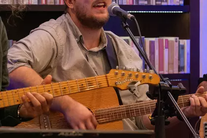 Muzyk grający na gitarze i śpiewający do mikrofonu.