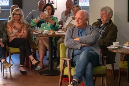 Uczestnicy spotkania słuchają rozmowy z poetą.