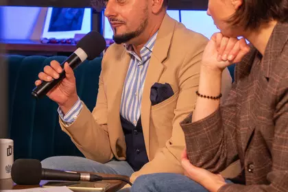 Prelegent wypowiada się podczas spotkania, trzymając mikrofon.