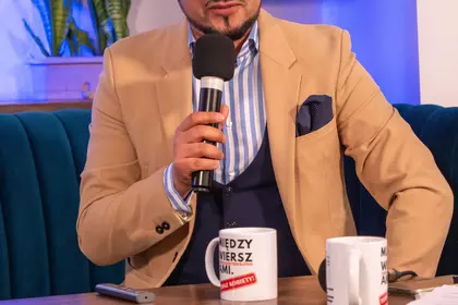 Prelegent opowiada na tle prezentacji multimedialnej.