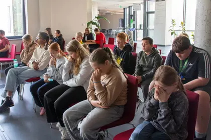 Uczestnicy warsztatów siedzą z zamkniętymi oczami, poznając perspektywę osób niewidomych.