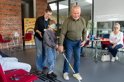 Prowadzący pokazuje dziecku, jak poruszać się z białą laską.